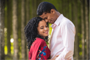 couple cuddling with trees in background. Remember why you are getting married in 4 months