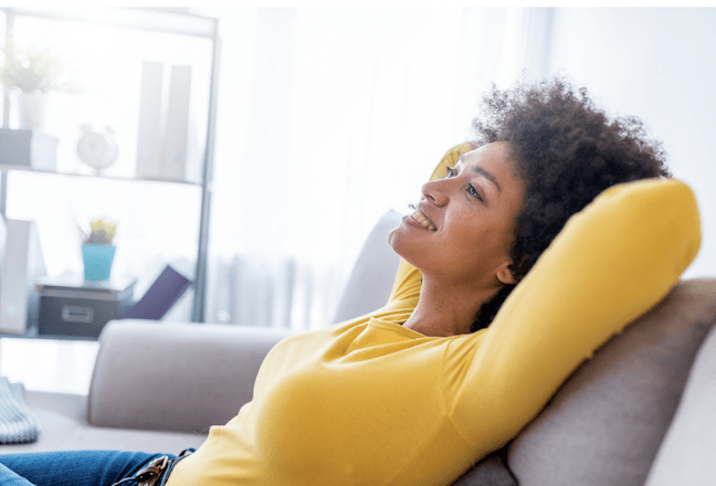 girl in yellow sweater relaxing at home as she is breaking the debt cycle to be debt free