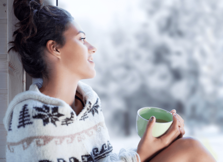 woman looking at snow in the window