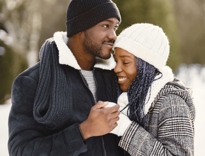 couple cuddling in the snow with their financial check in 