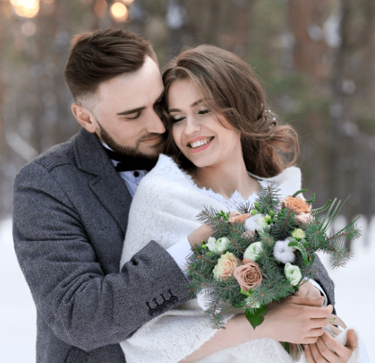 bride and groom cuddling in the snow 